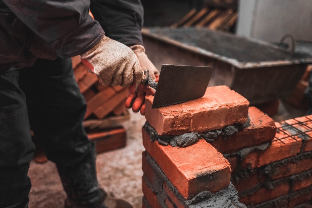 Bricklayer puts bricks to make a wall