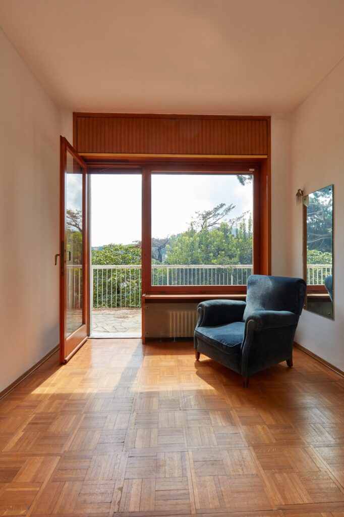 Sunny room interior with window and blue velvet armchair in country house